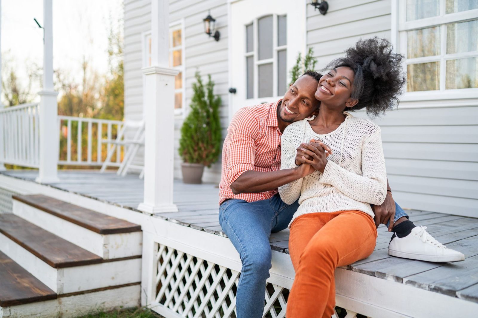 Couple sitting close together on their front porch, smiling